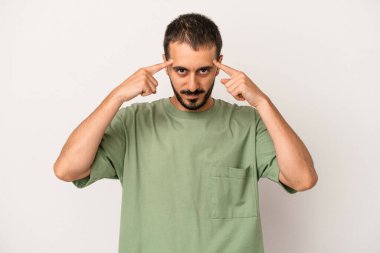 Beyaz arka planda izole edilmiş genç beyaz bir adam bir göreve odaklanmış, işaret parmaklarını işaret ediyor..