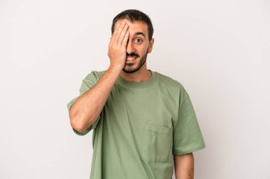 Beyaz arka planda izole edilmiş genç beyaz bir adam yüzünün yarısını palmiye ile örterek eğleniyor..