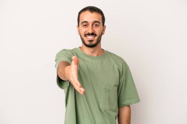 Beyaz arka planda izole edilmiş genç beyaz bir adam selamlama jesti olarak kameraya elini uzatıyor..