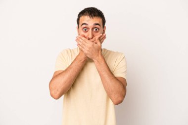 Beyaz arka planda izole edilmiş genç beyaz adam elleriyle ağzını kapatırken şok oldu..