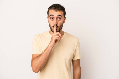 Beyaz arka planda izole edilmiş genç beyaz bir adam ya sır saklıyor ya da sessizlik istiyor..