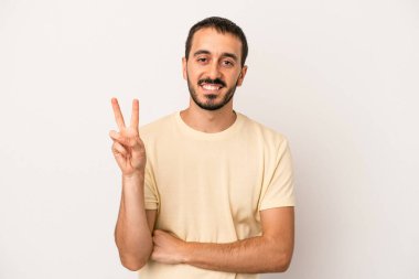 Beyaz arka planda izole edilmiş genç beyaz adam iki numarayı parmaklarıyla gösteriyor..