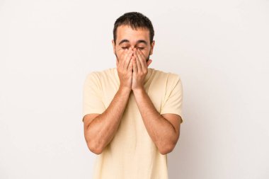 Beyaz arka planda izole olmuş genç beyaz bir adam bir şeye gülüyor, ağızlarını ellerle kapatıyor..