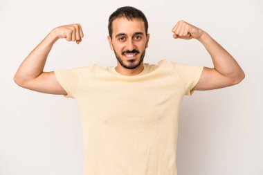 Beyaz arka planda izole edilmiş genç beyaz bir adam güçlü bir hareket gösteriyor, kollarıyla, kadınsı gücün sembolü.