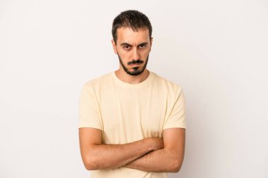 Beyaz arka planda izole edilmiş genç beyaz adam alaycı bir ifadeyle kameraya bakıyor..