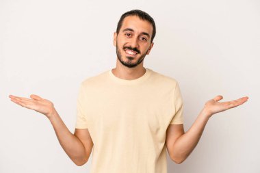 Beyaz arka planda izole genç beyaz adam kollarıyla ölçek yapar, mutlu ve kendinden emin hisseder..