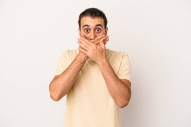 Beyaz arka planda izole edilmiş genç beyaz bir adam ağzı kapalı ve elleri endişeli görünüyor..