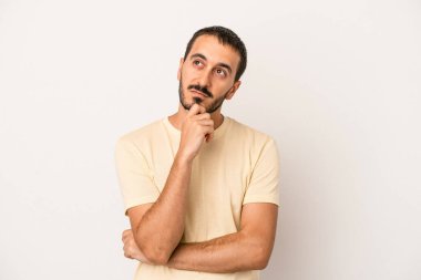 Beyaz arka planda soyutlanmış genç beyaz bir adam düşünüyor ve yukarı bakıyor, yansıtıyor, düşünüyor, hayal kuruyor..