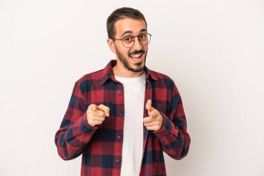 Beyaz arka planda izole edilmiş genç beyaz adam parmaklarıyla ön tarafı işaret ediyor..