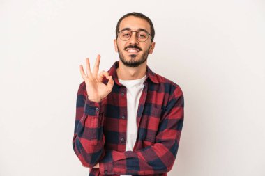 Beyaz arka planda izole edilmiş genç beyaz bir adam bir göz kırptı ve elleriyle iyi bir jest yaptı..