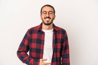 Beyaz arka planda izole edilmiş genç beyaz adam karnına dokunuyor, nazikçe gülümsüyor, yemek yiyor ve tatmin oluyor..