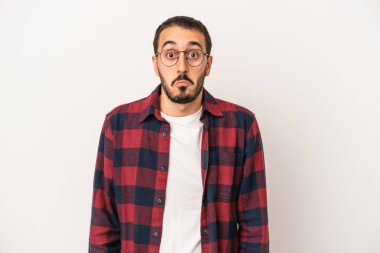 Beyaz arka planda izole edilmiş genç beyaz bir adam omuz silkiyor ve gözleri açık..