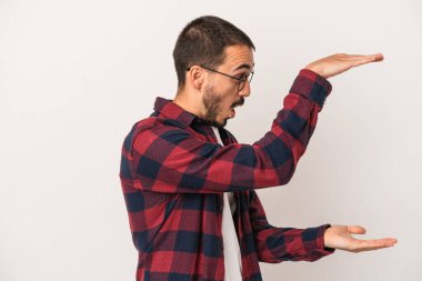 Beyaz arka planda izole edilmiş genç beyaz adam elleri arasında bir kopya alanı tutarken şok ve hayrete düştü..