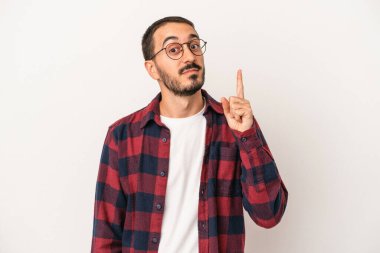 Beyaz arka planda izole edilmiş beyaz tenli genç bir adam bir numarayı parmağıyla gösteriyor..