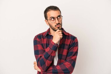 Beyaz arka planda izole edilmiş genç beyaz bir adam rahatlamış bir şeyin fotokopi odasına baktığını düşünüyor..