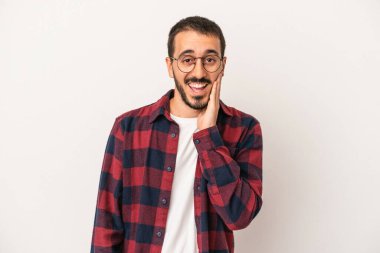 Beyaz arka planda izole genç beyaz adam yüksek sesle bağırıyor, gözleri açık ve elleri gergin tutuyor..