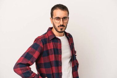 Beyaz arka planda izole edilmiş, hoşnutsuzca kaşlarını çatmış, kollarını kavuşturmuş genç beyaz bir adam..