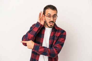 Beyaz arka planda izole edilmiş genç beyaz adam bir dedikoduyu dinlemeye çalışıyor..