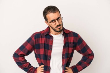 Beyaz arka planda soyutlanmış genç beyaz bir adam kafası karışmış, şüpheli ve güvensiz hissediyor..