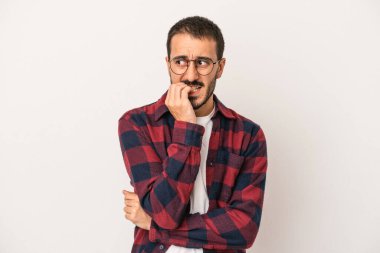 Beyaz arka planda izole edilmiş, tırnak yiyen, gergin ve endişeli genç bir beyaz adam..