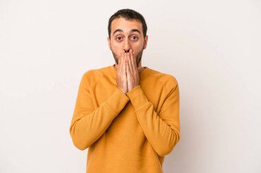 Beyaz arka planda izole edilmiş genç beyaz adam elleriyle ağzını kapatırken şok oldu..
