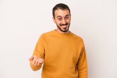 Beyaz arka planda izole edilmiş genç beyaz bir adam selamlama jesti olarak kameraya elini uzatıyor..
