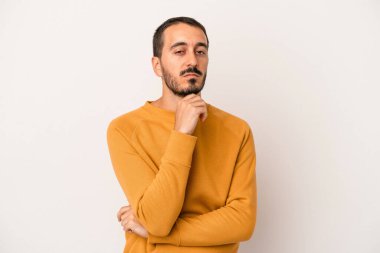 Beyaz arka planda izole edilmiş genç beyaz bir adam şüpheli, belirsiz, seni muayene ediyor..