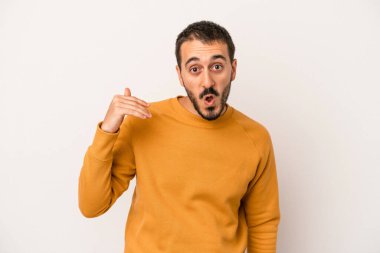 Beyaz arka planda izole olmuş genç beyaz bir adam bir şeye gülüyor, ağızlarını ellerle kapatıyor..