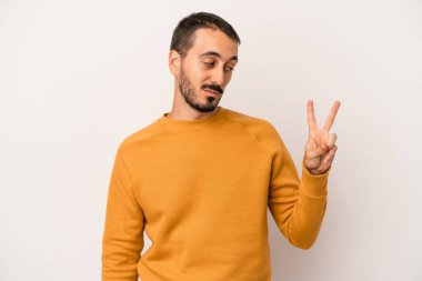 Beyaz arka planda izole edilmiş genç beyaz bir adam neşeli ve kaygısız parmakları olan bir barış sembolü gösteriyor..