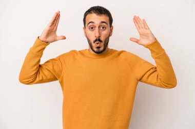 Beyaz arka planda izole olmuş genç beyaz bir adam zaferi veya başarıyı kutluyor, şaşırıyor ve şok oluyor..