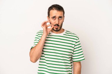Beyaz arka planda izole edilmiş beyaz tenli genç bir adam parmakları dudaklarında bir sır saklıyor..