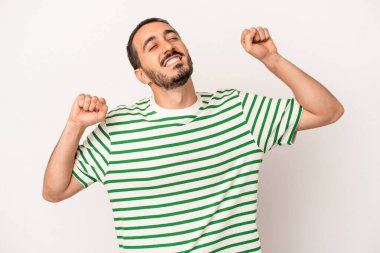 Beyaz arka planda izole genç beyaz adam özel bir günü kutluyor, atlıyor ve enerjiyle kollarını kaldırıyor..