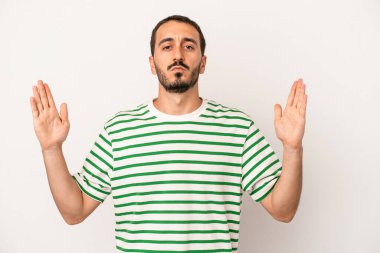 Beyaz arka planda izole edilmiş genç beyaz bir adam işaret parmaklarıyla küçük bir şey tutuyor, gülümsüyor ve kendinden emin..