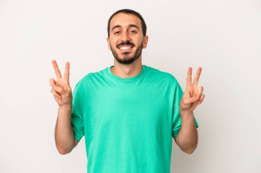 Beyaz arka planda izole edilmiş genç beyaz bir adam zafer işareti gösteriyor ve gülümsüyor..