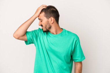 Beyaz arka planda izole edilmiş genç beyaz bir adam bir şeyi unutuyor. Alnına avuç içi ve gözlerini kapayarak vuruyor..