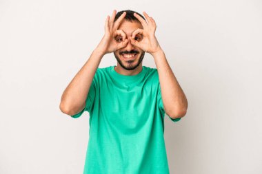 Beyaz arka planda izole genç beyaz adam heyecanlı tamam göz jesti tutmak.