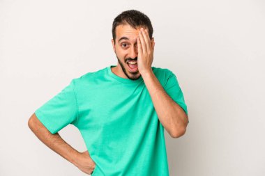 Beyaz arka planda izole edilmiş genç beyaz bir adam yüzünün yarısını palmiye ile örterek eğleniyor..