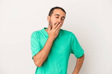 Beyaz arka planda izole edilmiş genç beyaz adam esniyor. Ağzı eliyle kapatan yorgun bir hareket sergiliyor..