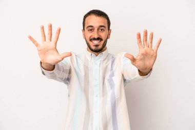 Beyaz arka planda izole edilmiş beyaz tenli genç adam on numarayı elleriyle gösteriyor..