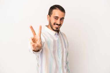 Beyaz arka planda izole edilmiş genç beyaz bir adam neşeli ve kaygısız parmakları olan bir barış sembolü gösteriyor..