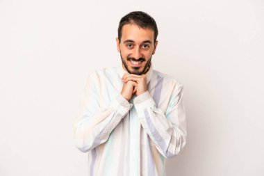 Beyaz arka planda izole genç beyaz adam ellerini çenesinin altında tutuyor, mutlu bir şekilde yana bakıyor..