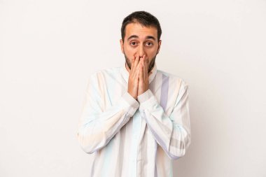 Beyaz arka planda izole edilmiş genç beyaz bir adam ağzı kapalı ve elleri endişeli görünüyor..