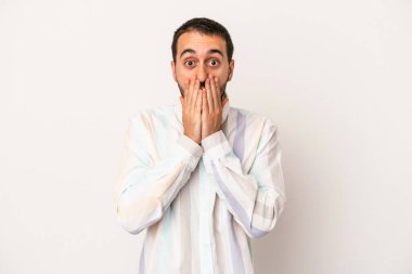 Beyaz arka planda izole edilmiş genç beyaz adam şok olmuş, ağzı ellerle kaplanmış, yeni bir şey keşfetmeye hevesli..