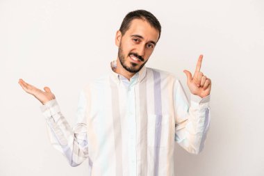 Beyaz arka planda izole edilmiş genç beyaz bir adam elinde bir ürün tutuyor ve.