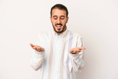 Beyaz arka planda izole edilmiş genç beyaz bir adam elinde avuç içi bir şeyle kameraya sunuyor..