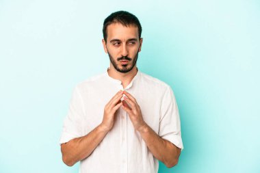 Kafkasyalı genç bir adam mavi arka planda izole edildi. Aklında bir plan kuruyor, bir fikir kuruyor..