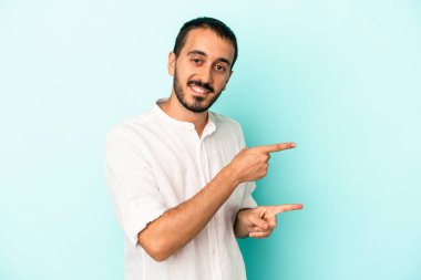 Kafkasyalı genç adam mavi arka planda izole edilmiş. İşaret parmağıyla işaret ettiği için heyecanlı..