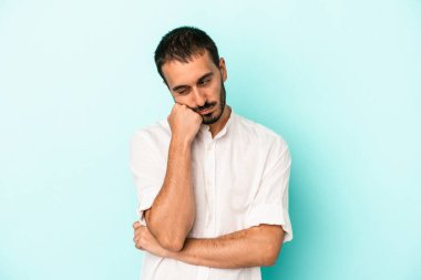 Mavi arka planda izole edilmiş, üzgün ve dalgın hisseden, kopyalama alanına bakan genç beyaz bir adam..