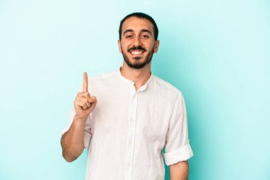 Mavi arka planda izole edilmiş genç beyaz adam bir numarayı parmağıyla gösteriyor..