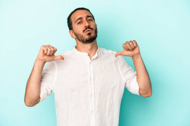 Mavi arka planda izole edilmiş genç beyaz adam gururlu ve kendinden emin hissediyor, örnek olarak.